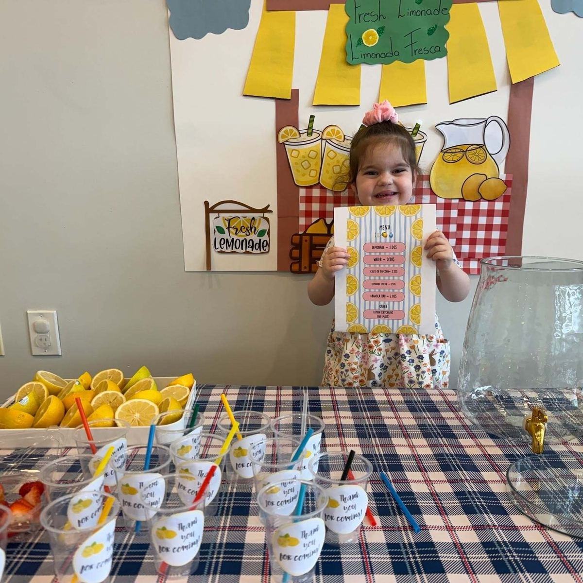 Child holding a bilingual lemonade stand menu at Park View Academy